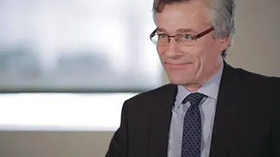 A man in a dark suit sitting for an interview